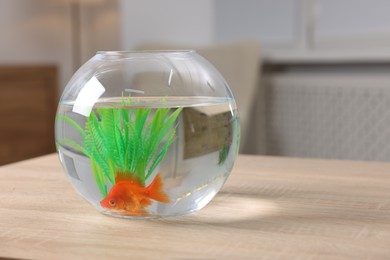 Photo of Goldfish in aquarium on wooden table indoors