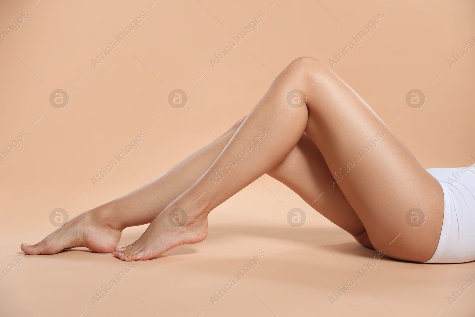 Photo of Woman with beautiful smooth legs after epilation on beige background, closeup