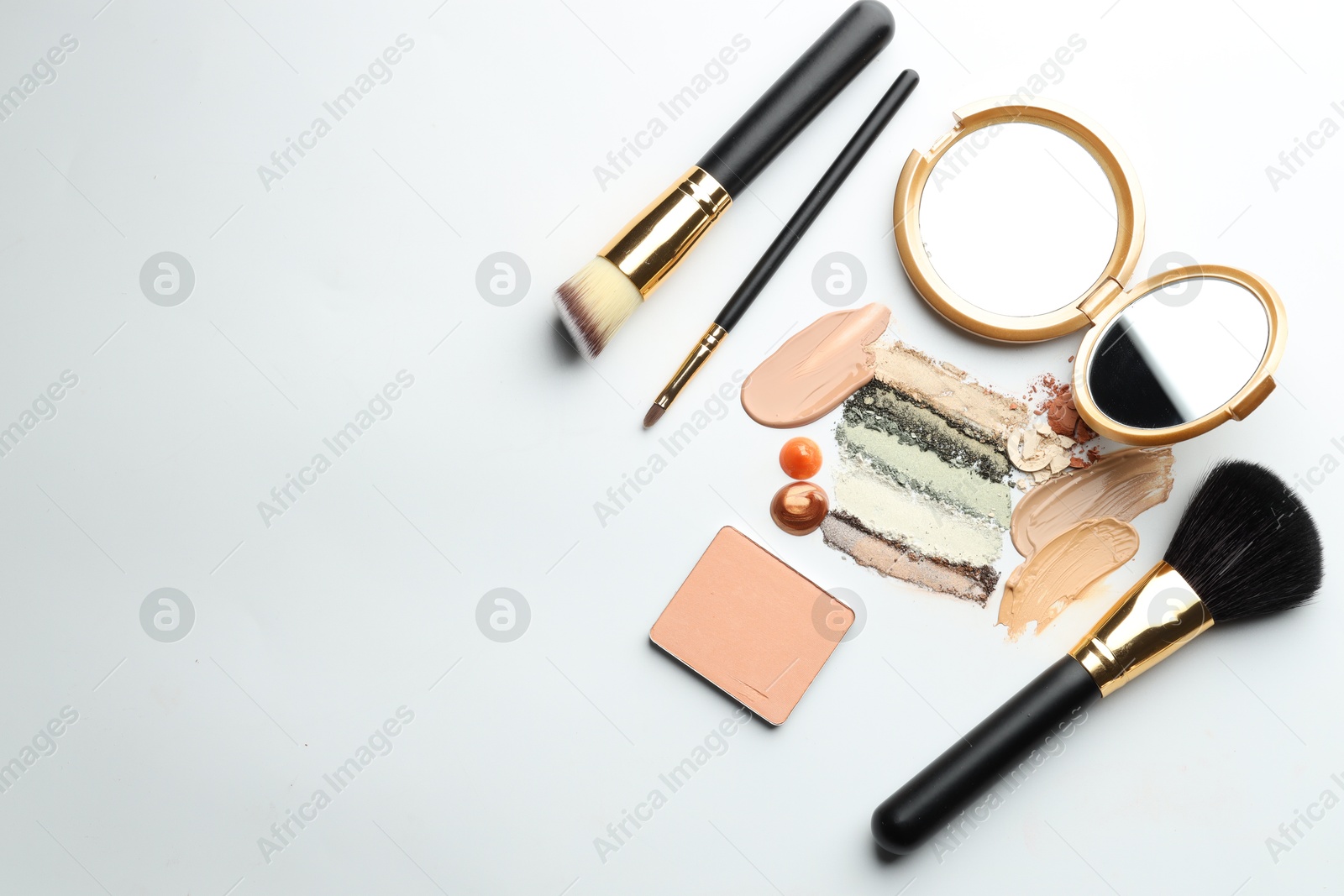 Different cosmetic products, makeup brushes and mirror on white background, flat lay. Space for text Photo of Different cosmetic products, makeup brushes and mirror on white background, flat lay. Space for text