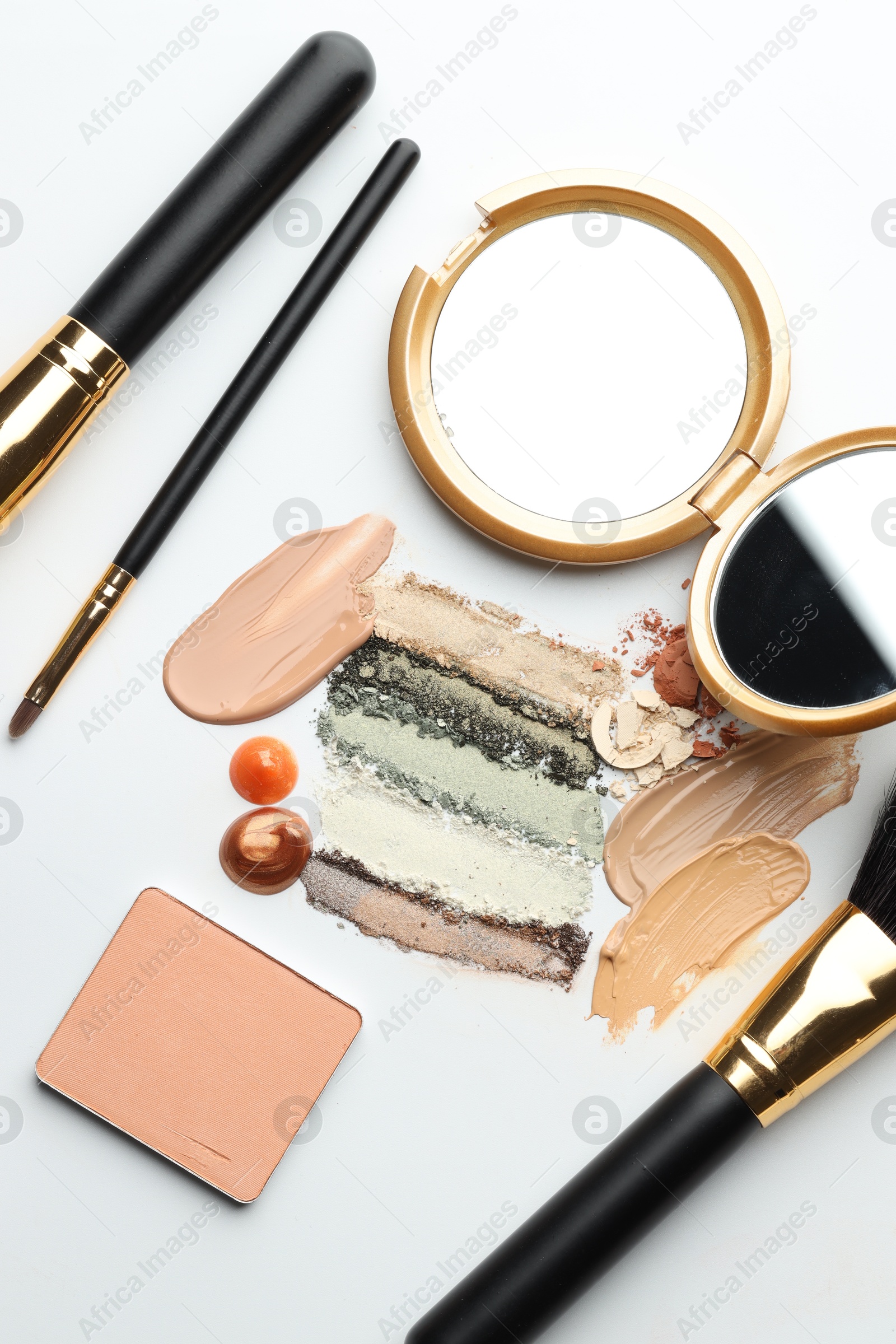 Different cosmetic products, makeup brushes and mirror on white background, flat lay Photo of Different cosmetic products, makeup brushes and mirror on white background, flat lay