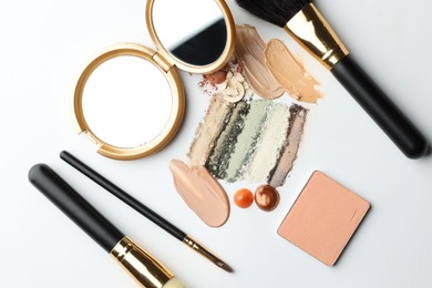 Photo of Different cosmetic products, makeup brushes and mirror on white background, flat lay