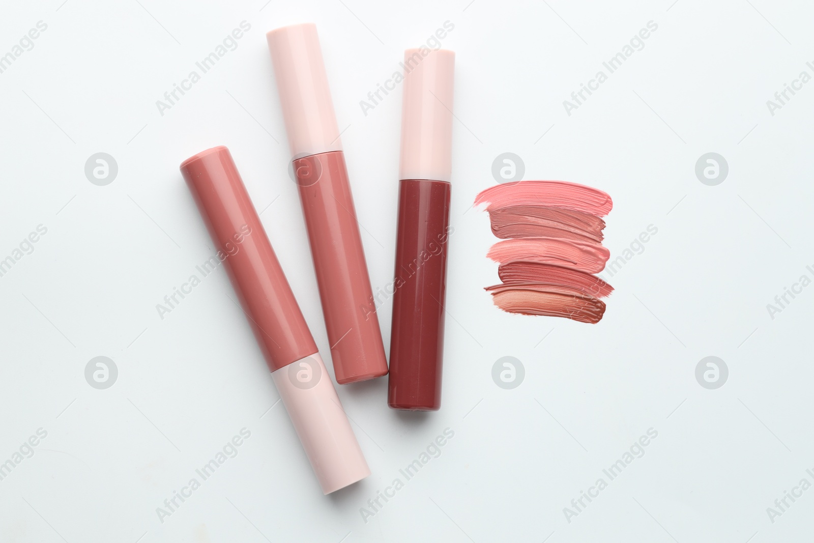 Colorful lip glosses on white background, flat lay Photo of Colorful lip glosses on white background, flat lay