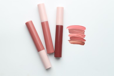 Photo of Colorful lip glosses on white background, flat lay