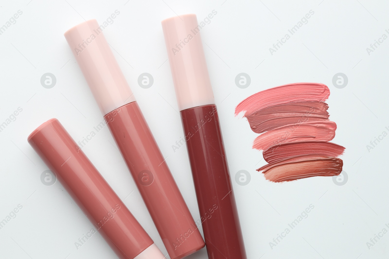 Colorful lip glosses on white background, flat lay Photo of Colorful lip glosses on white background, flat lay