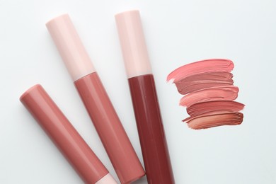 Photo of Colorful lip glosses on white background, flat lay