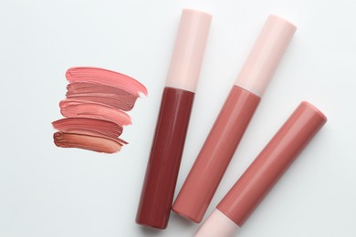 Photo of Colorful lip glosses on white background, flat lay