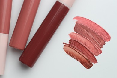 Photo of Colorful lip glosses on white background, flat lay