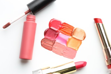 Photo of Colorful lip glosses and lipsticks on white background, flat lay