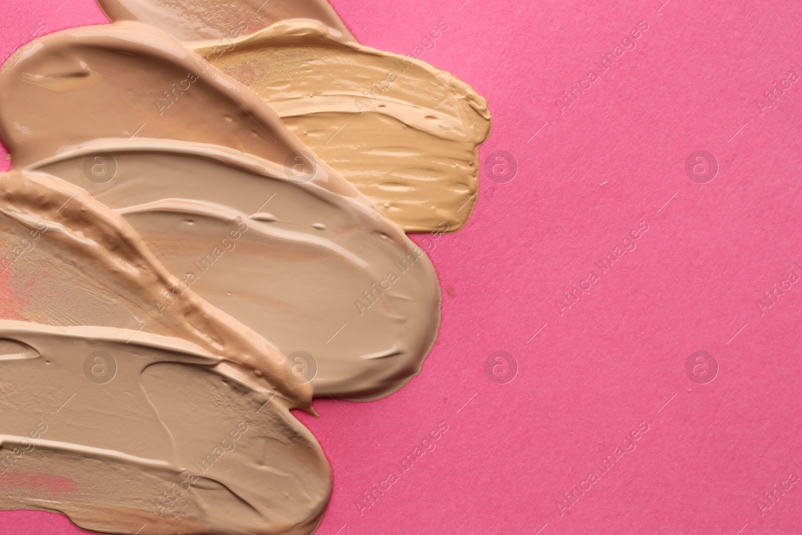Photo of Colorful skin foundations on magenta background, above view. Space for text