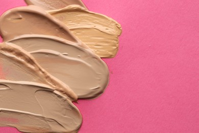 Photo of Colorful skin foundations on magenta background, above view. Space for text