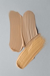 Photo of Colorful skin foundations on grey background, flat lay