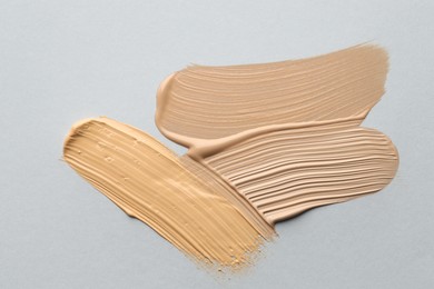 Photo of Colorful skin foundations on grey background, flat lay