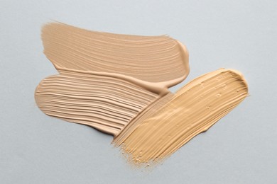 Photo of Colorful skin foundations on grey background, flat lay