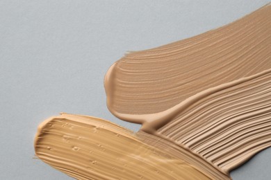 Photo of Colorful skin foundations on grey background, flat lay