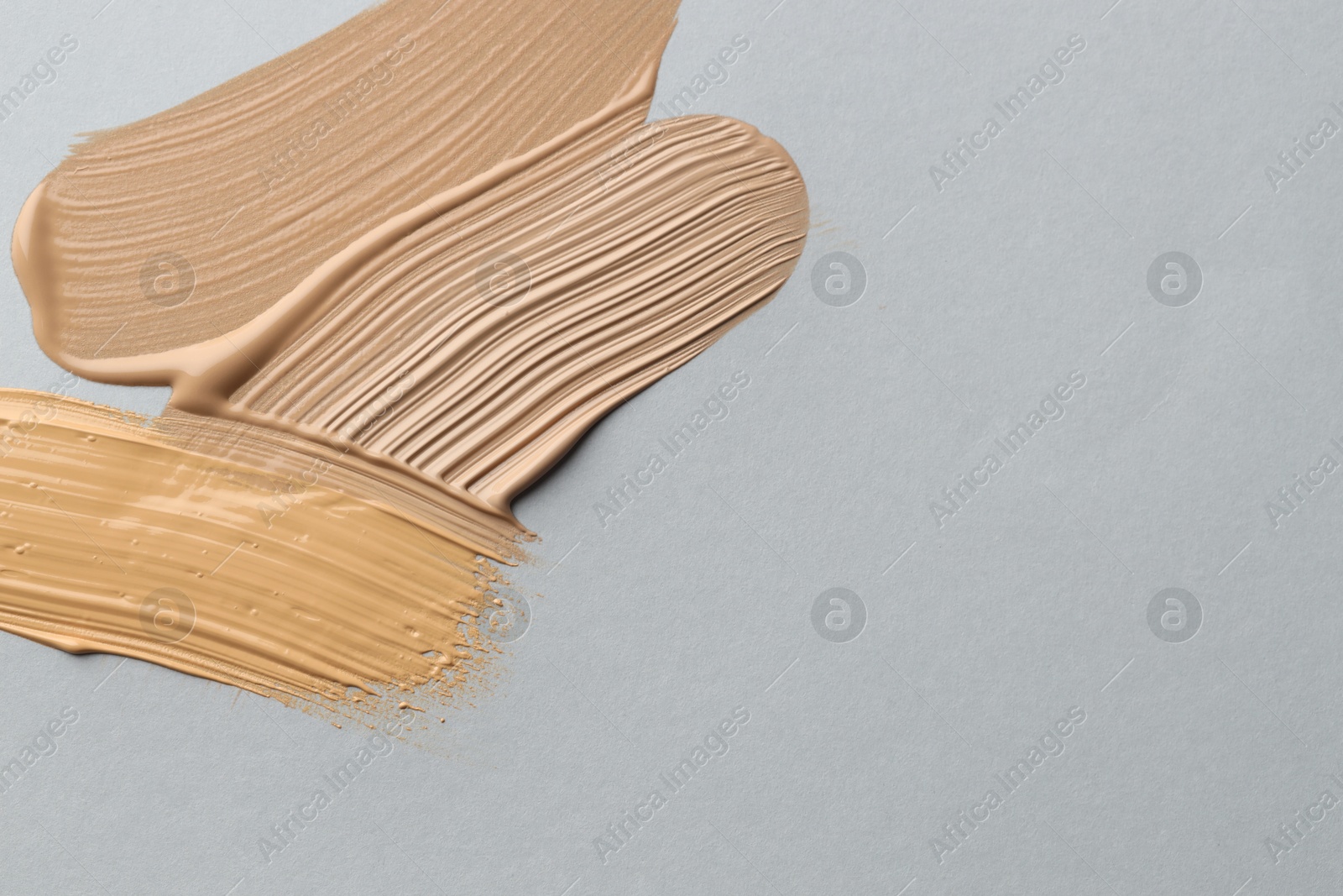 Colorful skin foundations on grey background, flat lay. Space for text Photo of Colorful skin foundations on grey background, flat lay. Space for text