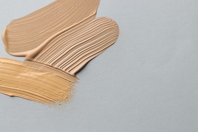 Photo of Colorful skin foundations on grey background, flat lay. Space for text