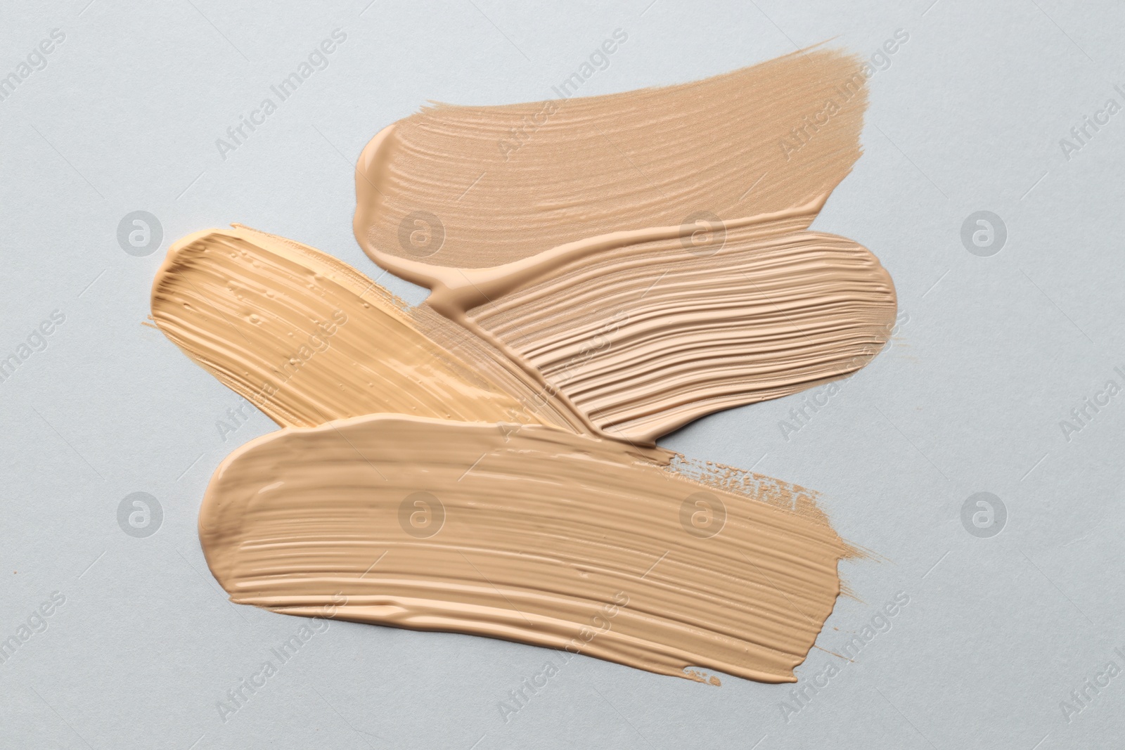 Photo of Colorful skin foundations on grey background, flat lay