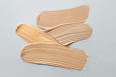Photo of Colorful skin foundations on grey background, flat lay