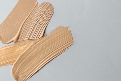 Photo of Colorful skin foundations on grey background, flat lay. Space for text