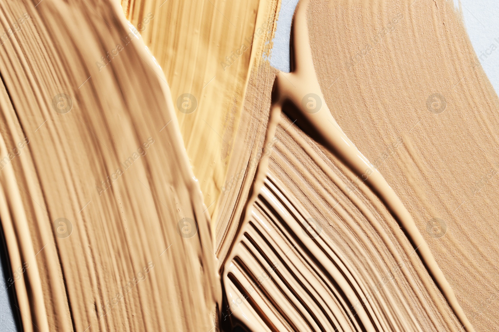 Photo of Colorful skin foundations on grey background, closeup