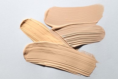 Photo of Colorful skin foundations on light grey background, above view