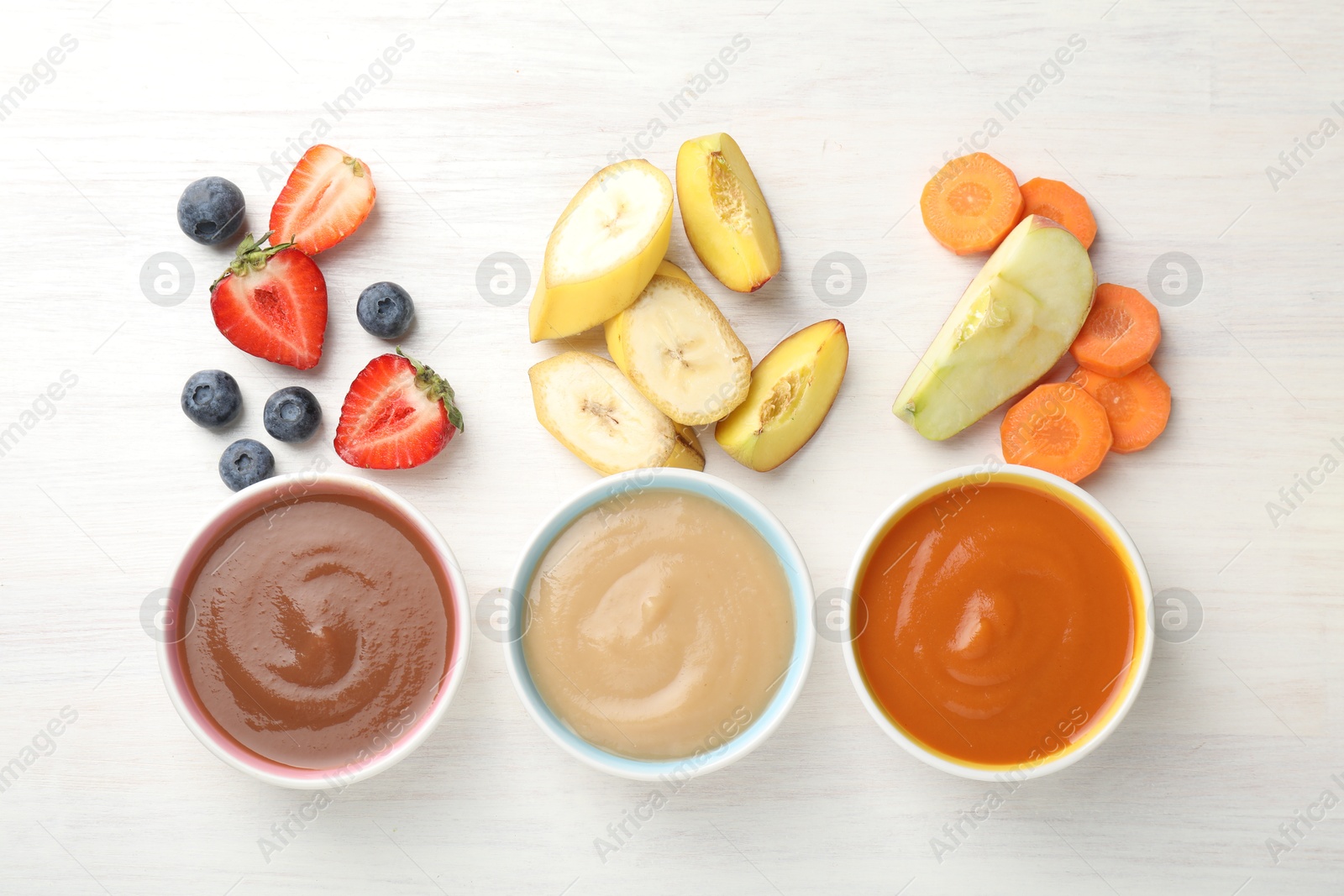Baby food. Tasty puree in bowls and different ingredients on white wooden table, flat lay Photo of Baby food. Tasty puree in bowls and different ingredients on white wooden table, flat lay