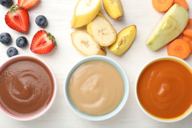 Photo of Baby food. Tasty puree in bowls and different ingredients on white wooden table, flat lay