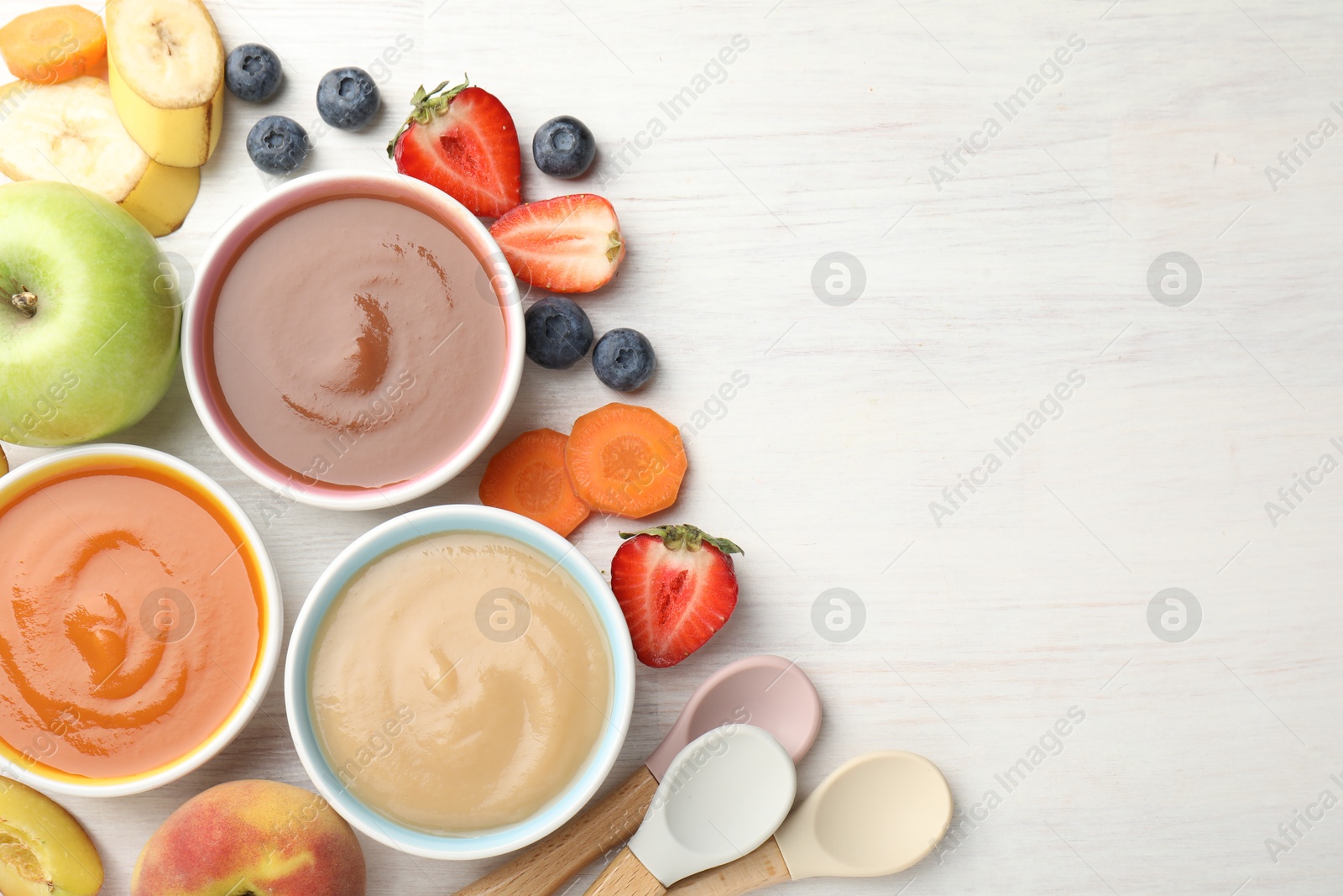 Baby food. Tasty puree in bowls and different ingredients on white wooden table, flat lay. Space for text Photo of Baby food. Tasty puree in bowls and different ingredients on white wooden table, flat lay. Space for text