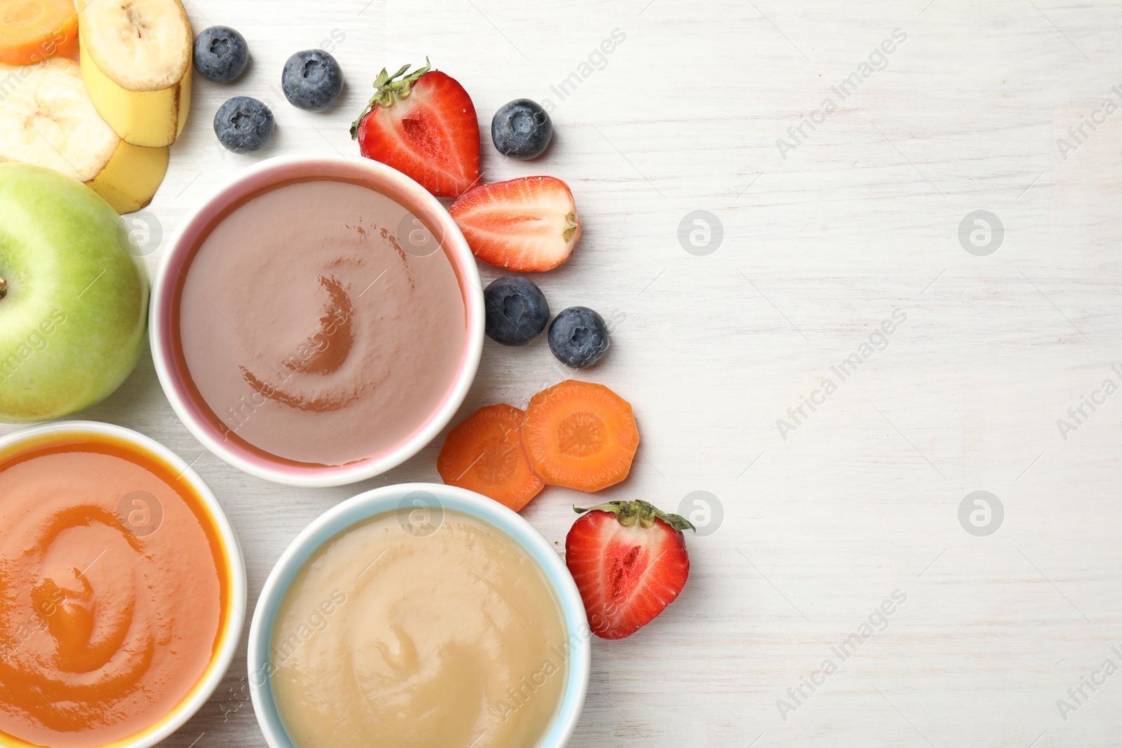 Baby food. Tasty puree in bowls and different ingredients on white wooden table, flat lay. Space for text Photo of Baby food. Tasty puree in bowls and different ingredients on white wooden table, flat lay. Space for text