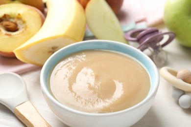 Photo of Baby food. Tasty puree in bowl, different ingredients, teether and pacifier on table, closeup