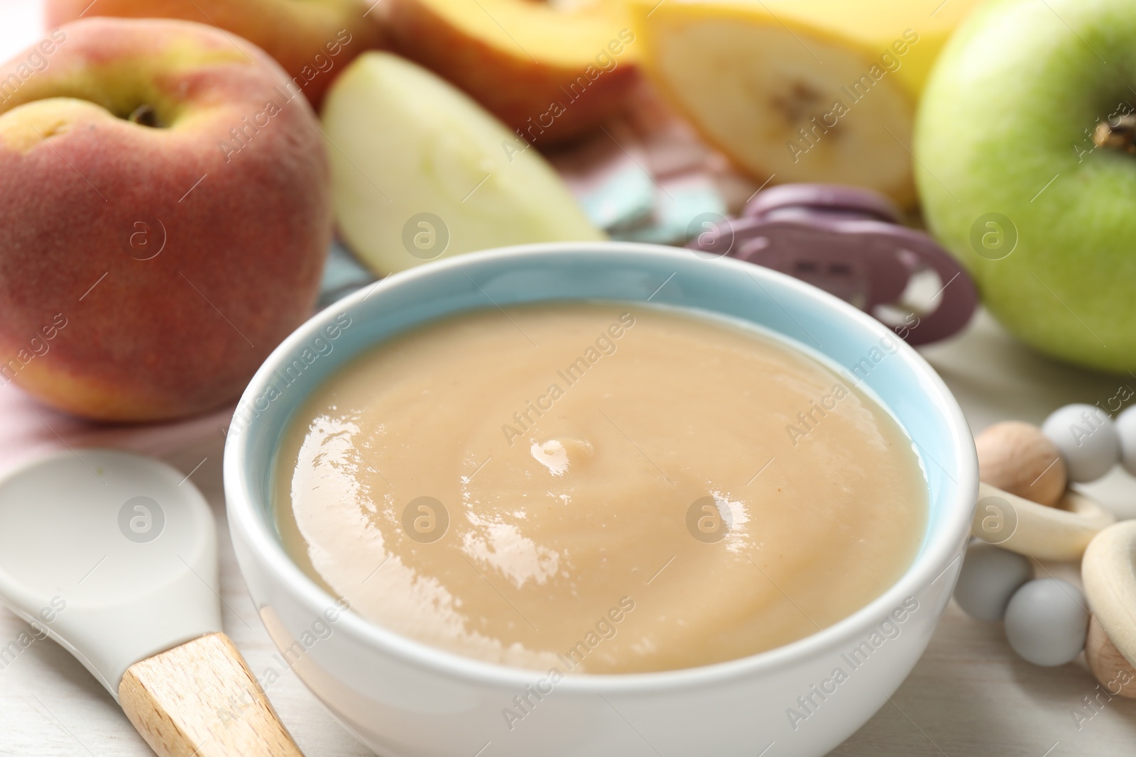 Baby food. Tasty puree in bowl, different ingredients, teether and pacifier on table, closeup Photo of Baby food. Tasty puree in bowl, different ingredients, teether and pacifier on table, closeup