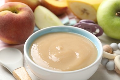 Photo of Baby food. Tasty puree in bowl, different ingredients, teether and pacifier on table, closeup