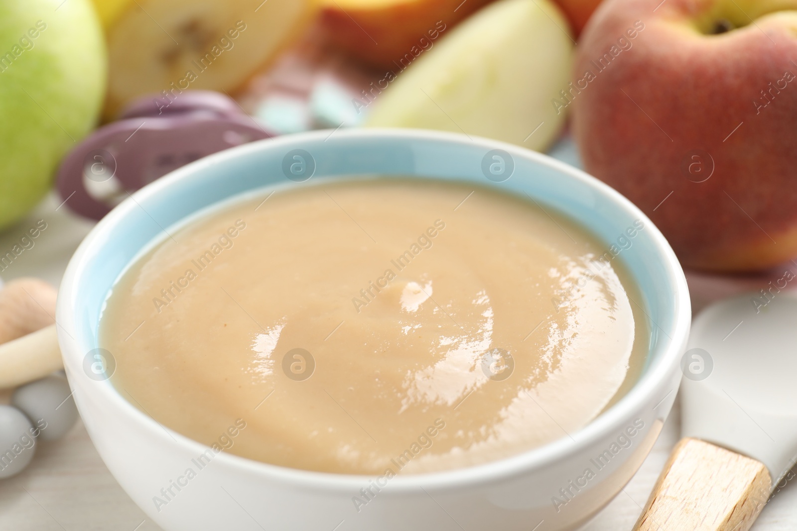 Baby food. Tasty puree in bowl, different ingredients, teether and pacifier on table, closeup Photo of Baby food. Tasty puree in bowl, different ingredients, teether and pacifier on table, closeup