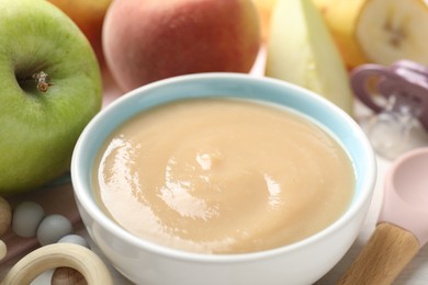 Photo of Baby food. Tasty puree in bowl, different ingredients, teether and pacifier on table, closeup