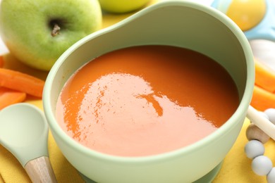 Photo of Baby food. Tasty puree in bowl, different ingredients and teether on table, closeup