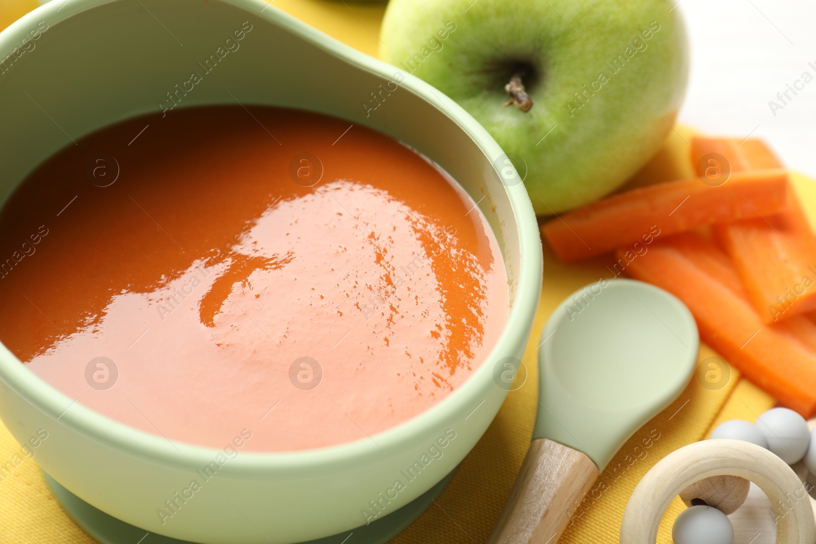 Baby food. Tasty puree in bowl, different ingredients and teether on table, closeup Photo of Baby food. Tasty puree in bowl, different ingredients and teether on table, closeup