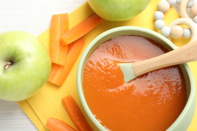 Photo of Baby food. Tasty puree in bowl, different ingredients and teether on table, flat lay
