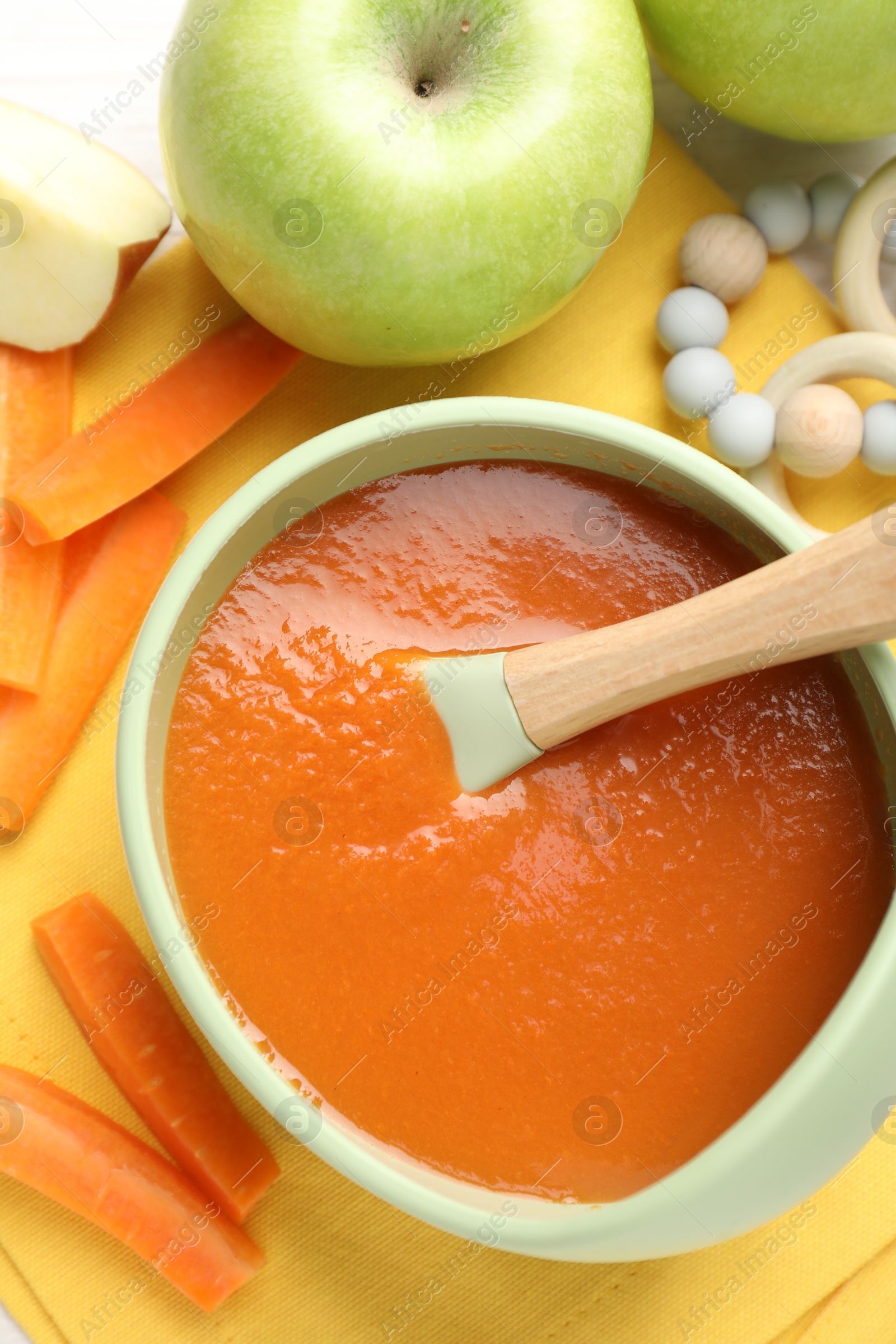 Baby food. Tasty puree in bowl, different ingredients and teether on table, flat lay Photo of Baby food. Tasty puree in bowl, different ingredients and teether on table, flat lay
