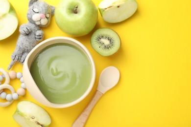 Photo of Baby food. Tasty puree in bowls, different ingredients and toys on yellow background, flat lay. Space for text