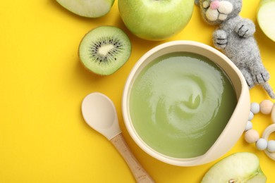 Photo of Baby food. Tasty puree in bowls, different ingredients and toys on yellow background, flat lay. Space for text