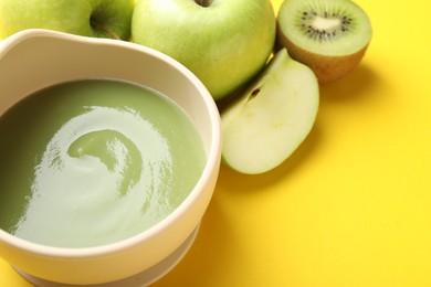 Photo of Baby food. Tasty puree in bowls and different ingredients on yellow background, above view. Space for text