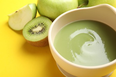 Photo of Baby food. Tasty puree in bowls and different ingredients on yellow background, closeup