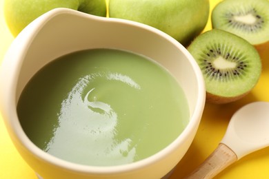 Photo of Baby food. Tasty puree in bowls and different ingredients on yellow background, closeup