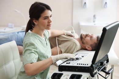 Photo of Sonographer conducting ultrasound examination of man's thyroid gland in clinic