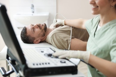 Photo of Sonographer conducting ultrasound examination of man's thyroid gland in clinic, closeup