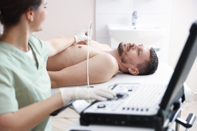 Photo of Sonographer conducting ultrasound examination of man's heart in clinic, closeup