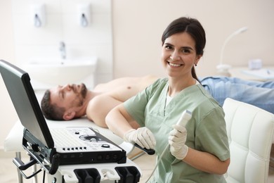 Photo of Sonographer with ultrasound transducer and man waiting for examination in clinic, selective focus