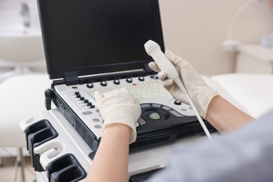 Photo of Sonographer with transducer and ultrasound machine in clinic, closeup
