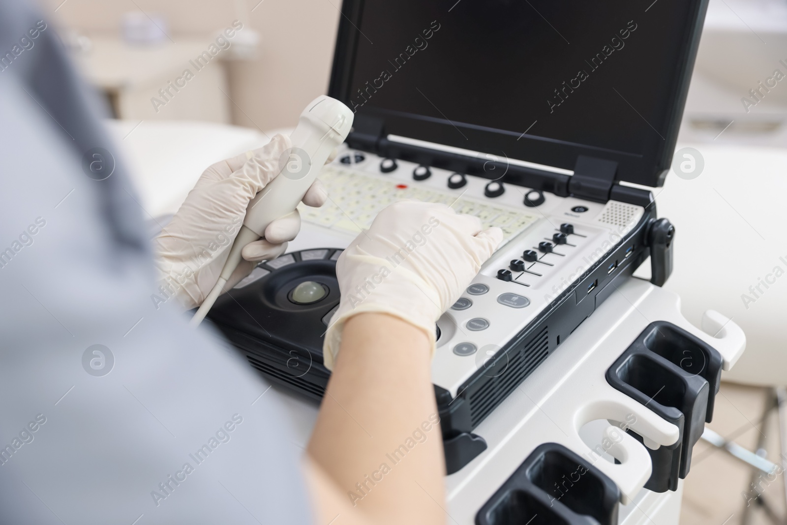 Photo of Sonographer with transducer and ultrasound machine in clinic, closeup