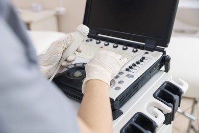 Photo of Sonographer with transducer and ultrasound machine in clinic, closeup